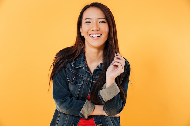 Photo gratuite heureuse femme asiatique en veste en jean tenant ses cheveux