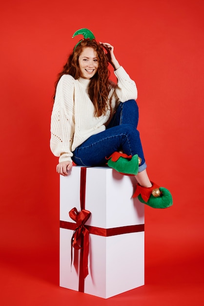 Heureuse femme assise sur un grand cadeau de Noël