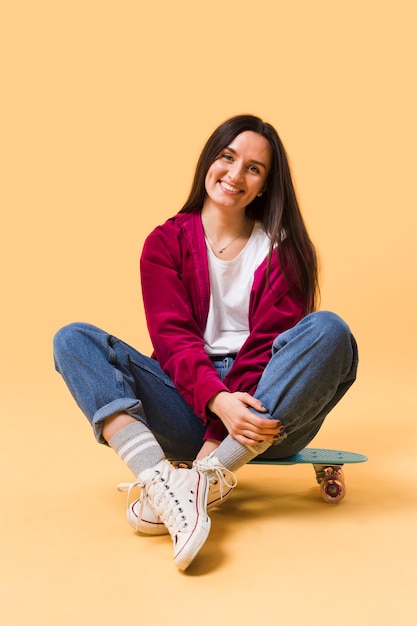 Heureuse femme assise sur une planche à roulettes