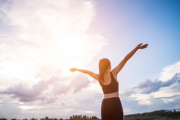 Heureuse femme athlétique souriante avec les bras tendus