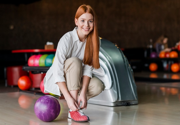 Heureuse femme attachant des lacets dans un club de bowling