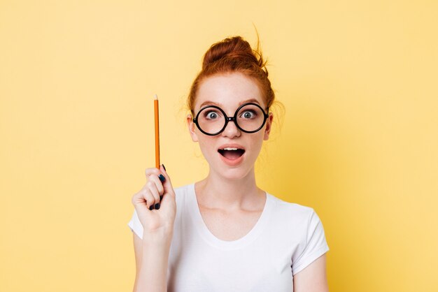 Heureuse femme au gingembre à lunettes ayant l'idée