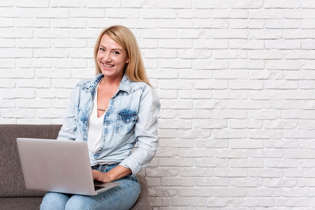 Heureuse femme blonde assise et regardant la caméra