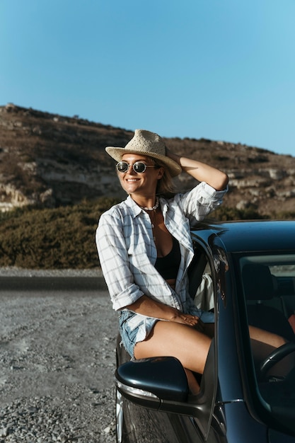 Heureuse femme blonde debout hors de la fenêtre de la voiture