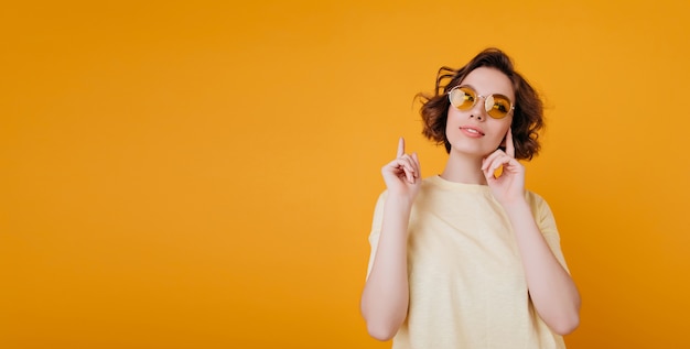 Heureuse femme brune avec une coiffure ondulée rêveuse à la recherche de suite