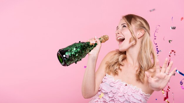 Heureuse femme chantant à la bouteille de champagne