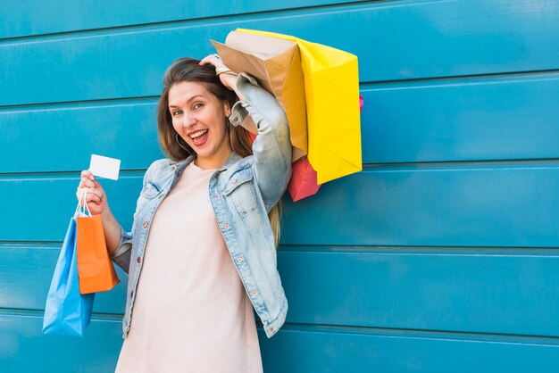 Heureuse femme debout avec des sacs à provisions et carte de crédit