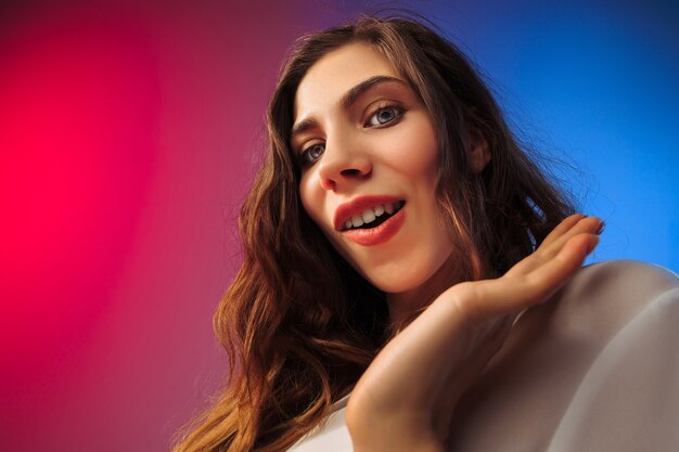 Heureuse femme debout, souriant sur fond de studio coloré. Beau portrait de femme demi-longueur.