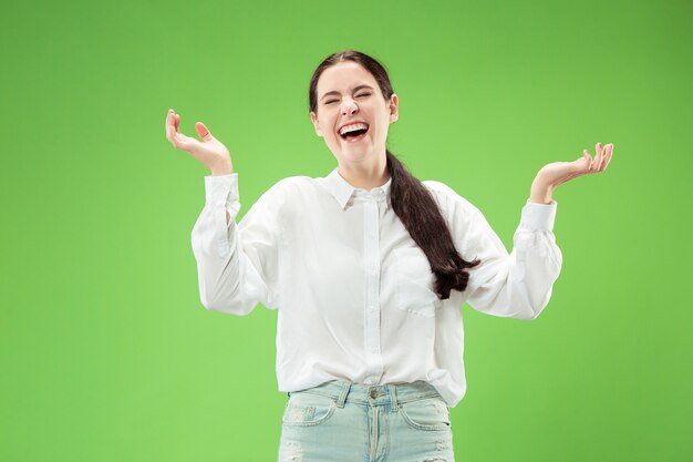 Heureuse femme debout et souriant isolé sur fond de studio vert. Beau portrait de femme demi-longueur.