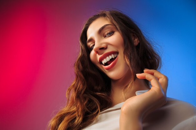 Heureuse femme debout, souriant sur studio coloré.