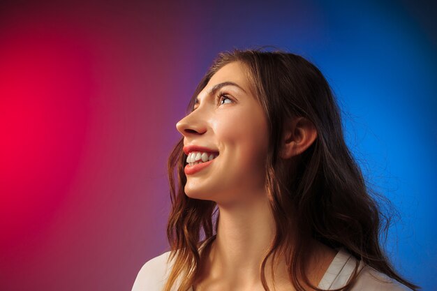 Heureuse femme debout, souriant sur studio coloré.