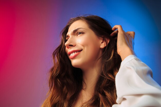 Heureuse femme debout, souriant sur studio coloré