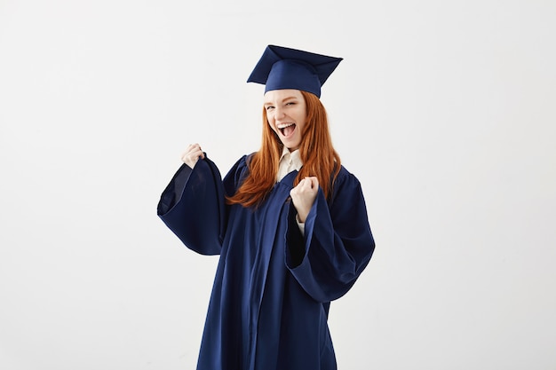 Heureuse femme diplômée en manteau se réjouissant de rire en souriant.