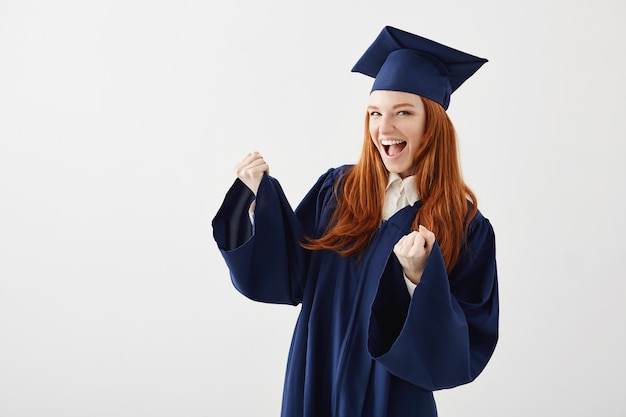 Heureuse femme diplômée en manteau se réjouissant de rire en souriant.