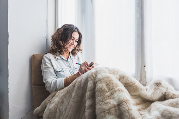 Photo gratuite heureuse femme écrit par la fenêtre