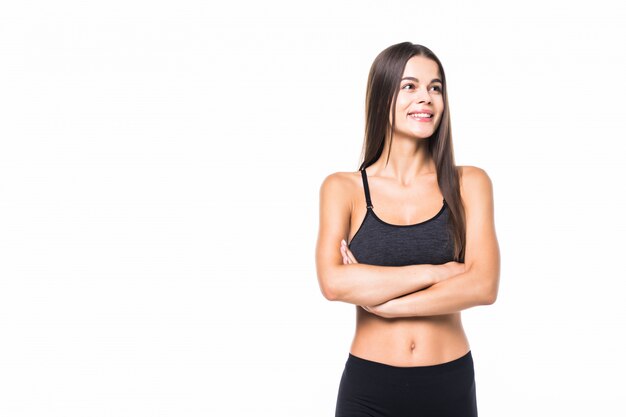 Heureuse femme fitness debout avec les bras croisés sur blanc