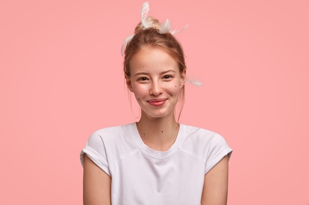 Heureuse femme heureuse heureuse de recevoir du café au lit de l'amant, vêtue d'un t-shirt décontracté, a des plumes sur la tête