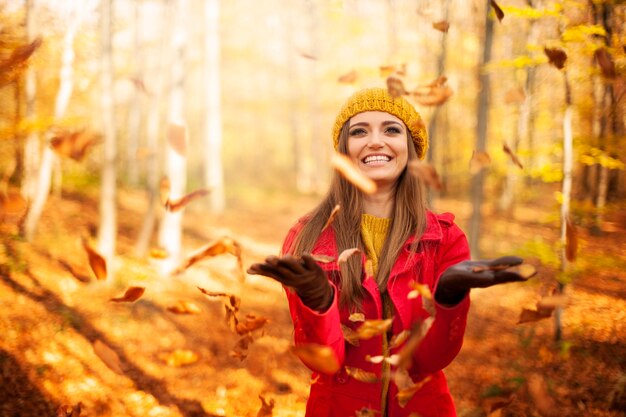 Heureuse femme jetant des feuilles