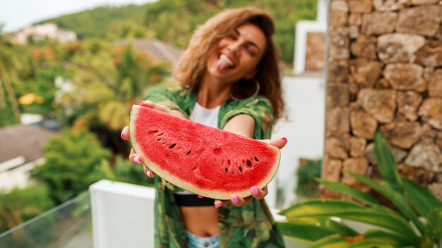 Heureuse femme mignonne avec des cheveux ondulés tenant la pastèque.