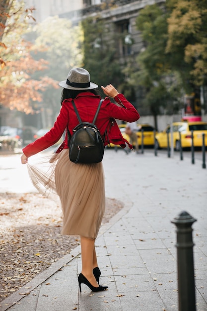 Photo gratuite heureuse femme mince en chaussures à talons hauts noirs dansant dans le parc en journée d'automne