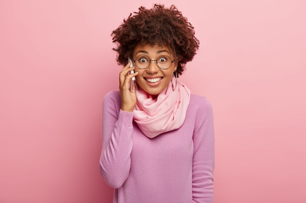 Photo gratuite heureuse femme noire positive appelle un ami pour la communication et discuter de certains détails
