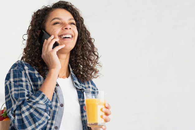 Heureuse femme parlant au téléphone et buvant du jus