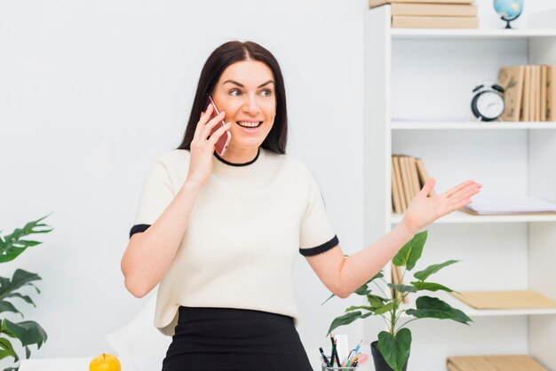 Heureuse femme parlant par téléphone au bureau