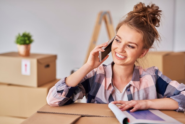 Heureuse femme parlant par téléphone mobile parmi les boîtes