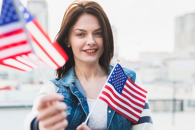 Heureuse femme patriotique montrant des drapeaux américains