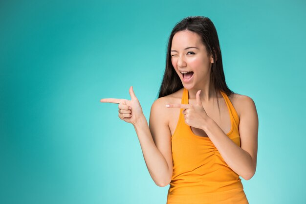 Heureuse femme pointant de côté et un clin de œil