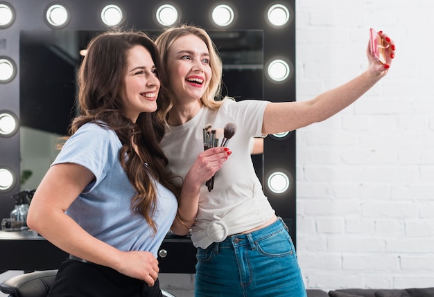 Heureuse femme prenant selfie dans le miroir de maquillage