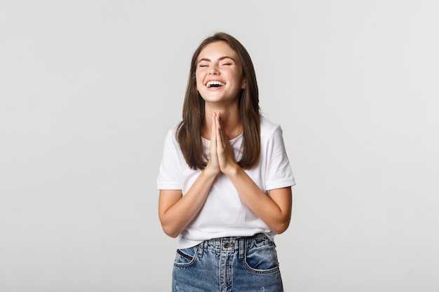 Heureuse femme reconnaissante et soulagée se tenant la main en priant, riant de joie.