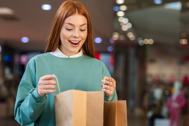 Photo gratuite heureuse femme regardant dans un sac à provisions