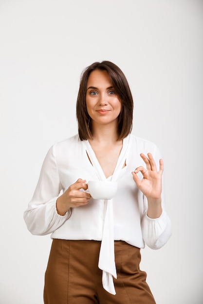 Heureuse femme réussie montrer bien, donner son approbation, boire du café