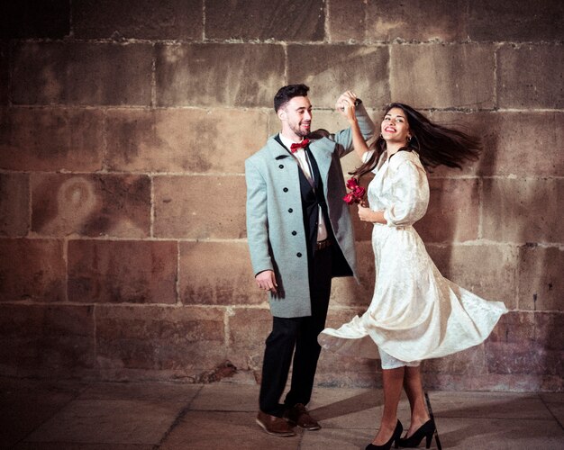 Heureuse femme en robe qui danse avec l&#39;homme dans la rue