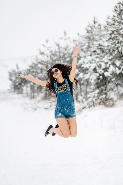 Heureuse femme sautant dans la forêt d&#39;hiver