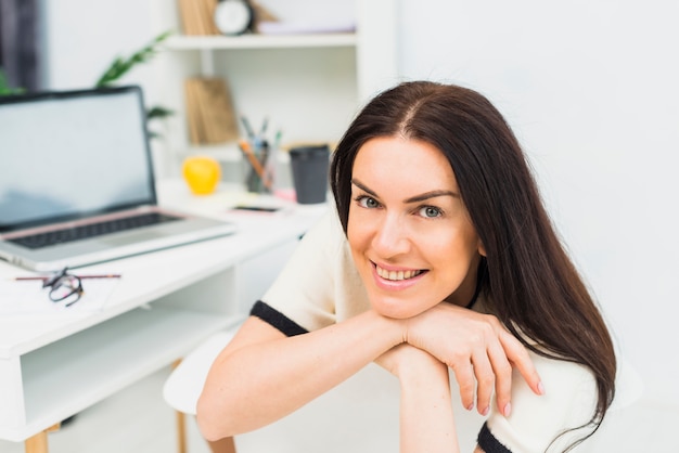 Heureuse femme se reposant sur une chaise au bureau