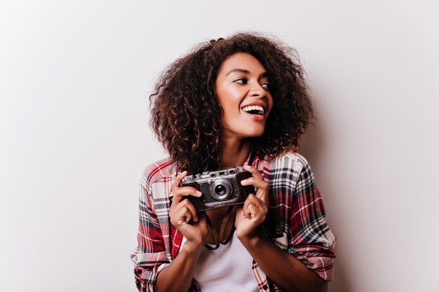 Heureuse femme shotgraphe glaçant. Femme afican rêveuse en chemise à carreaux tenant la caméra.