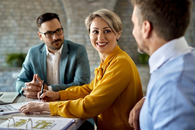 Heureuse femme signant un contrat tout en étant avec son mari lors d'une réunion avec un agent immobilier