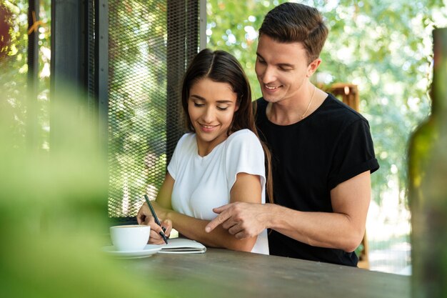 Heureuse femme souriante, prendre des notes dans un manuel