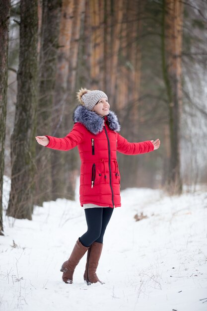 Heureuse femme souriante en veste d&#39;hiver rouge réjouissant à l&#39;extérieur