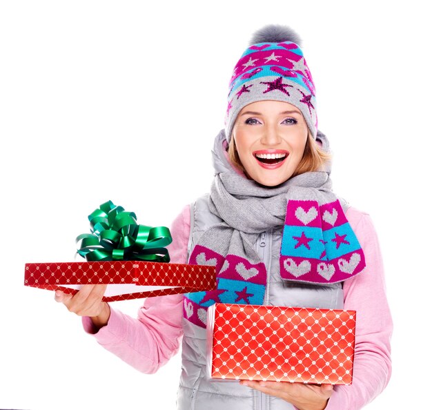 Heureuse femme surprise avec un cadeau de Noël dans un vêtement d'hiver isolé sur blanc