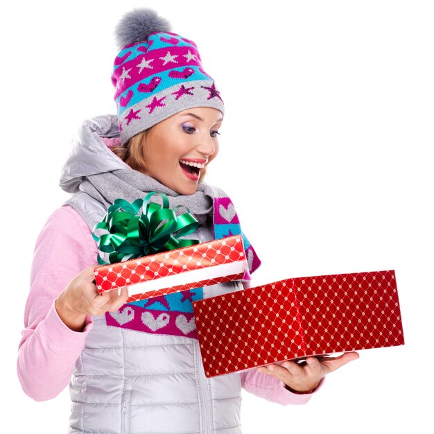 Heureuse femme surprise avec un cadeau de Noël dans un vêtement d'hiver isolé sur blanc