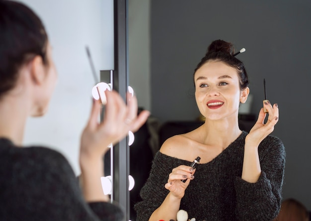 Heureuse femme tenant une baguette de mascara