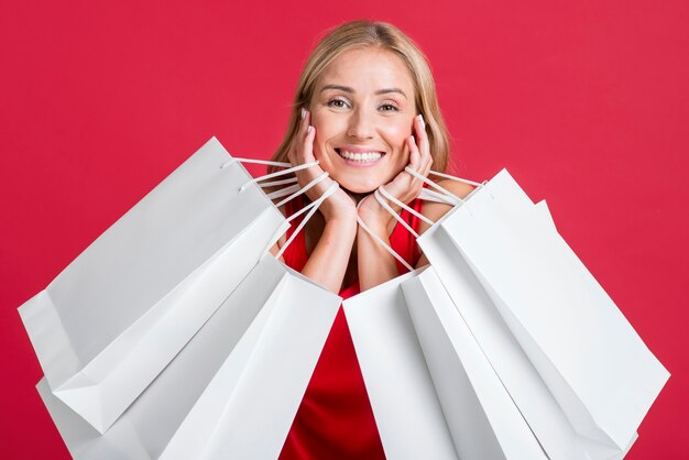 Heureuse femme tenant de nombreux sacs à provisions après une virée shopping