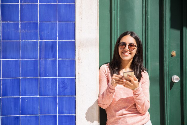 Heureuse femme utilisant un smartphone à l&#39;extérieur