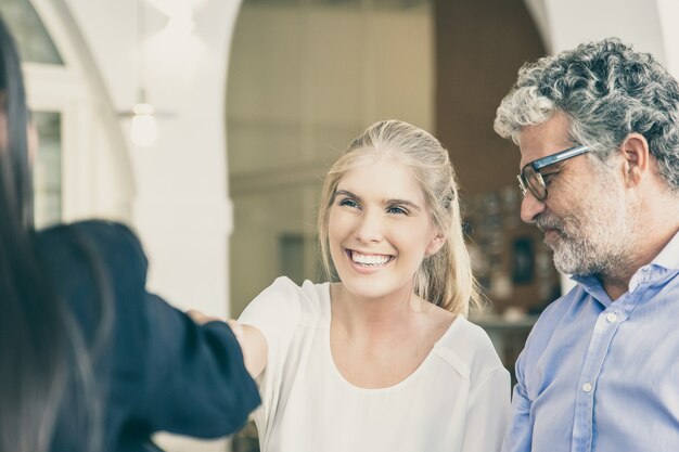 Heureuse fille adulte et père mûr rencontre avec un consultant familial au co-working, se serrant la main