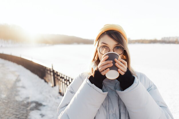 Heureuse jeune adolescente tenant une tasse de café à emporter