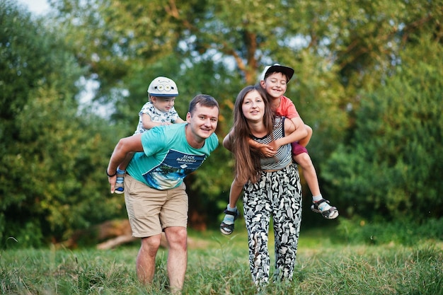 Heureuse jeune famille mère père deux enfants fils sur la nature s'amusant