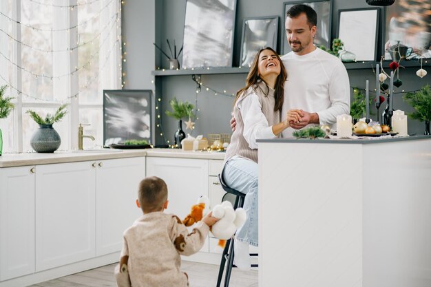 Heureuse jeune famille passant du temps ensemble dans la cuisine à la maison à Noël